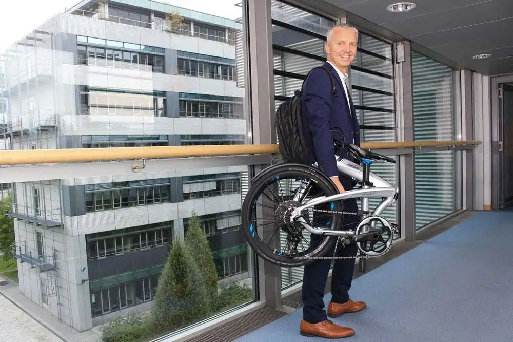 Mitarbeiter mit Faltrad gefaltet - Frank Noe Mitarbeiter mit Faltrad gefaltet - Frank Noe